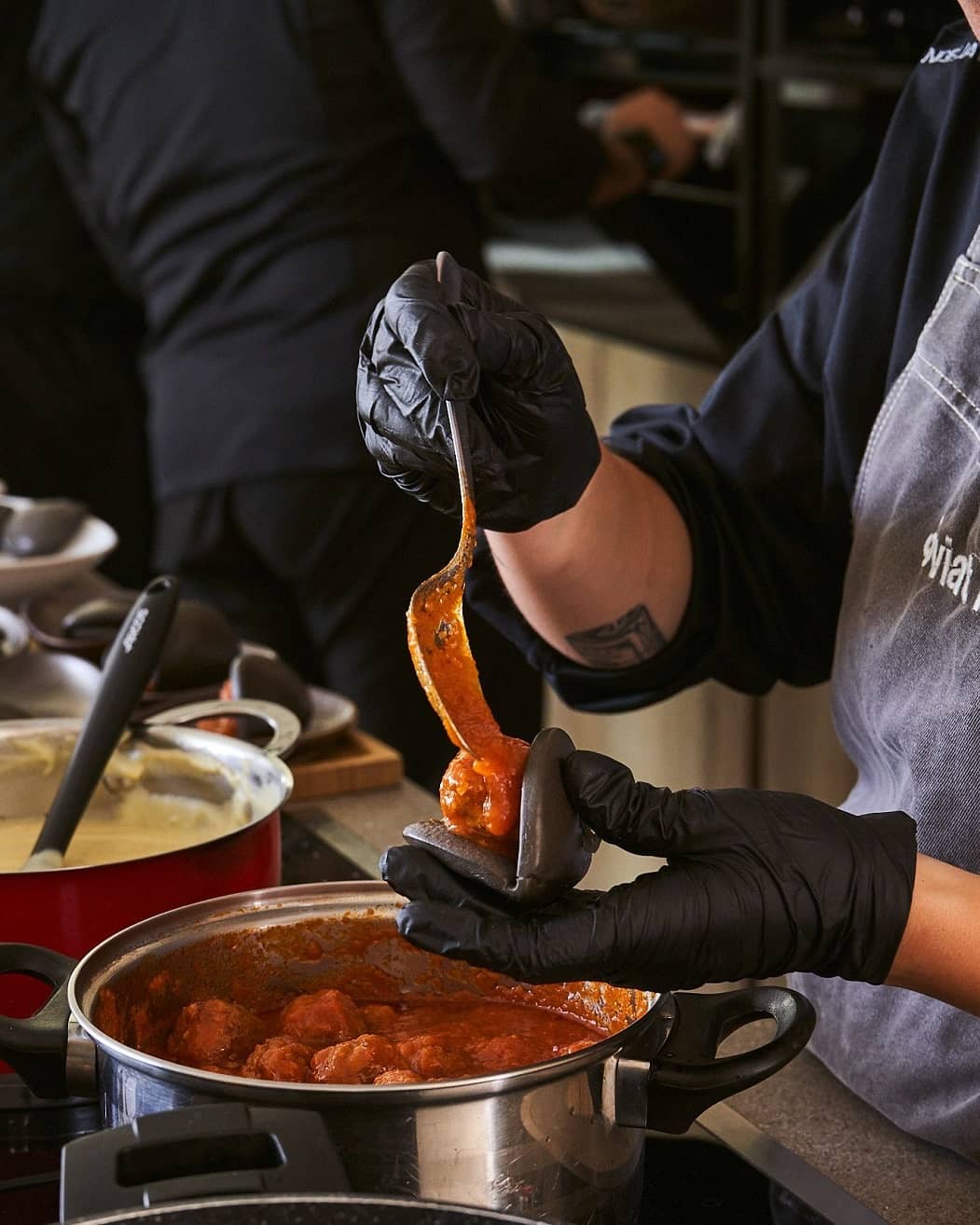 Cocinero emplatando albóndigas en la cocina de un evento