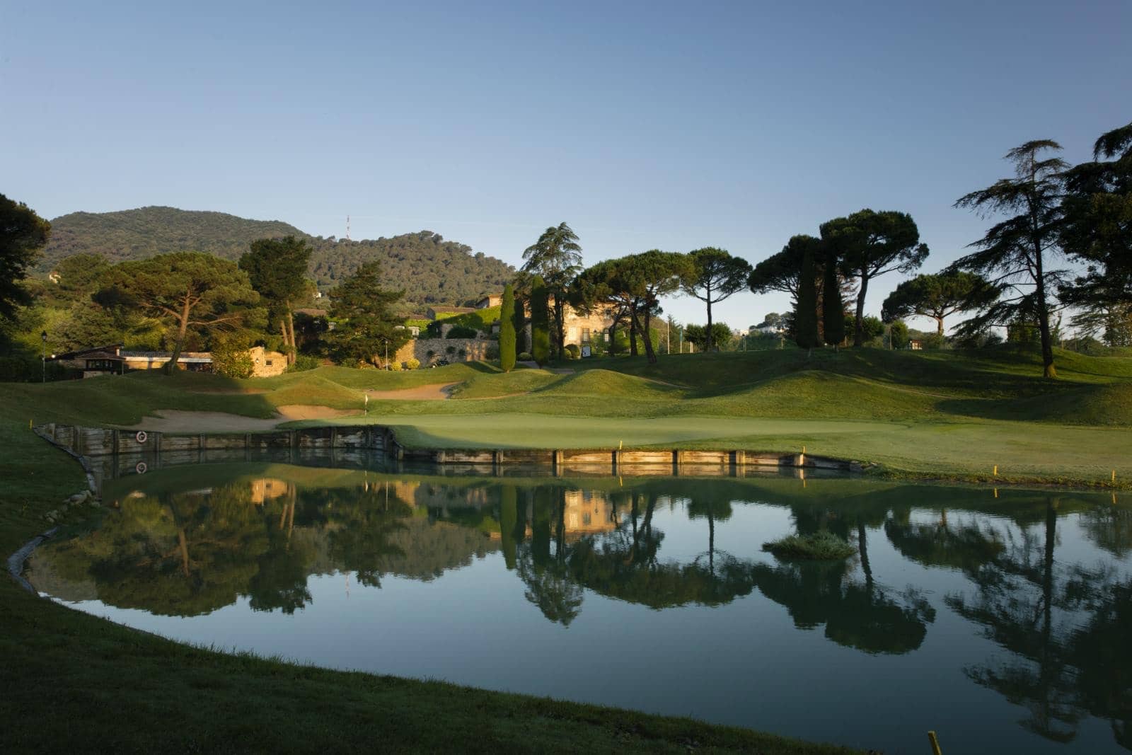 Club de golf junto a un lago con montañas al fondo