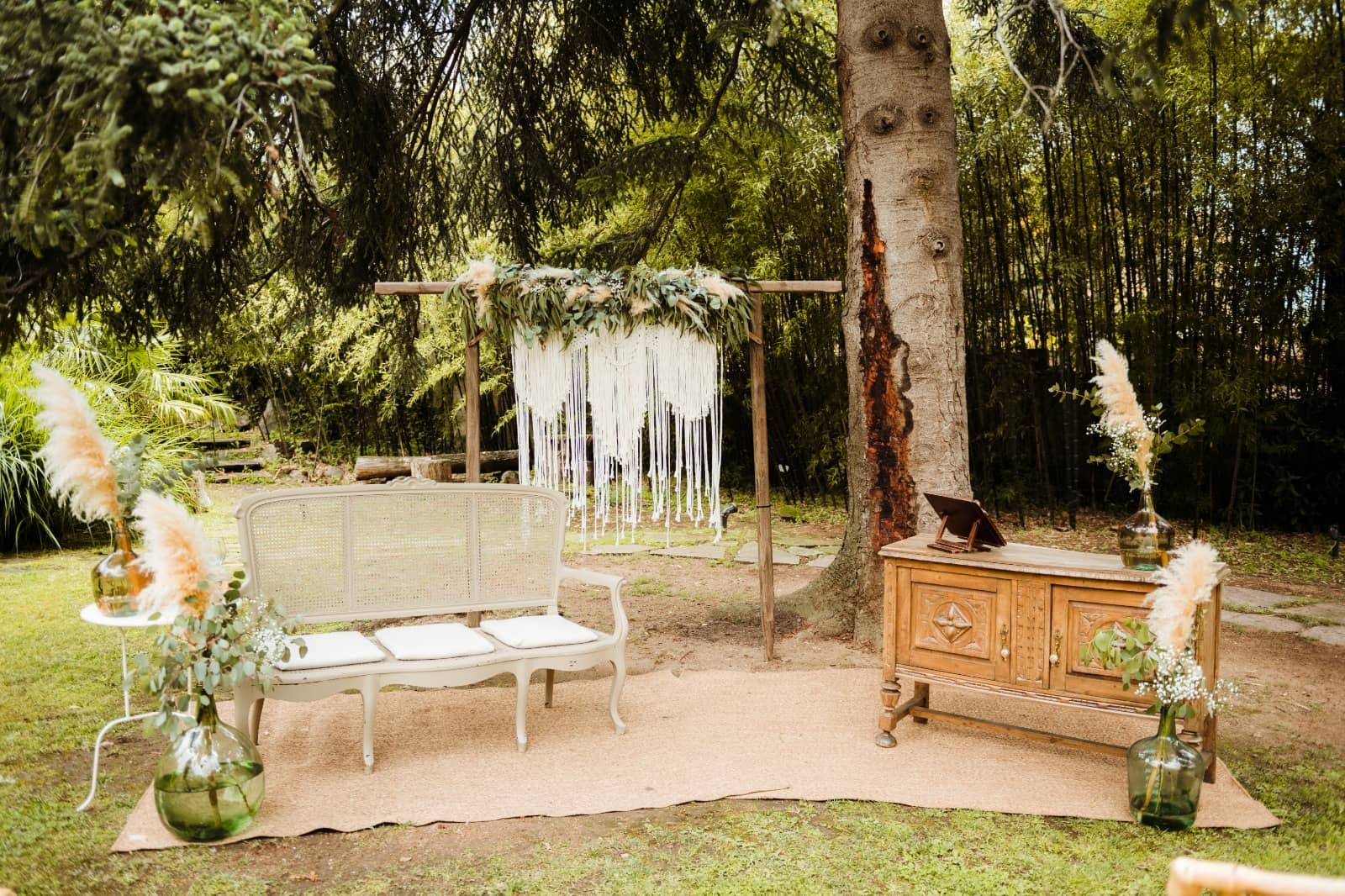 Rincón decorado en un jardín con sofá, macramé y pampas