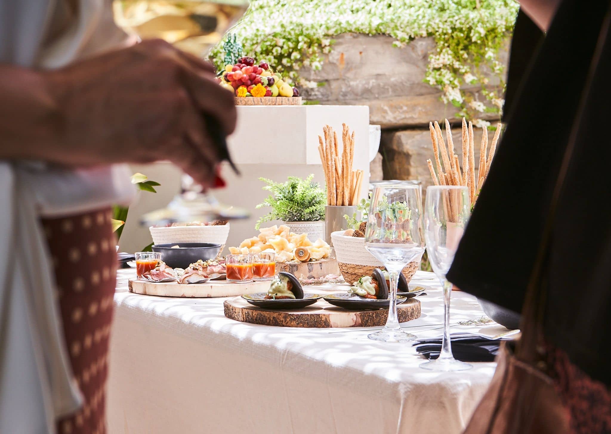 Mesa de aperitivos al aire libre con copas y vegetación