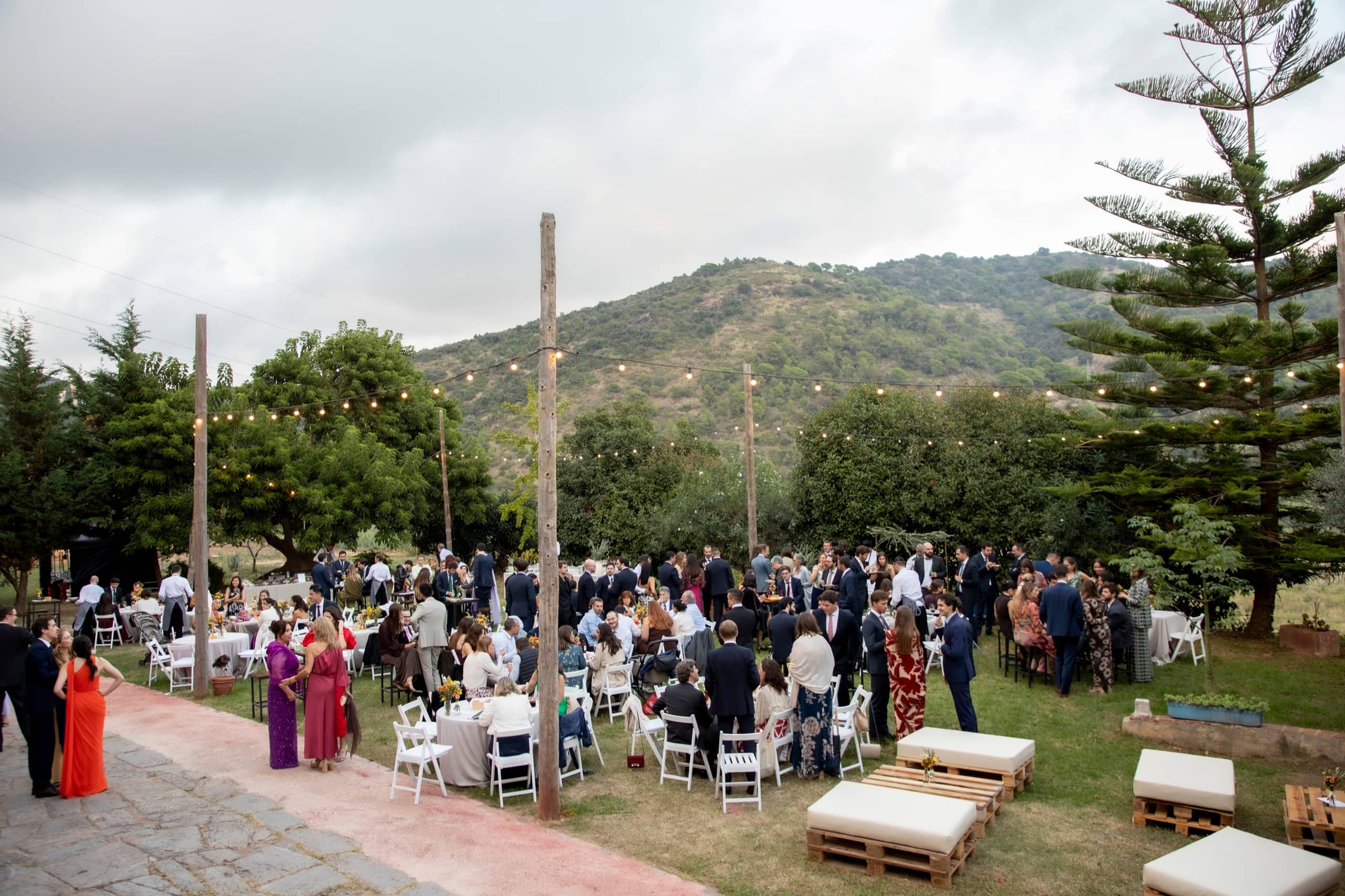 Invitados en un evento al aire libre con mesas y montañas al fondo
